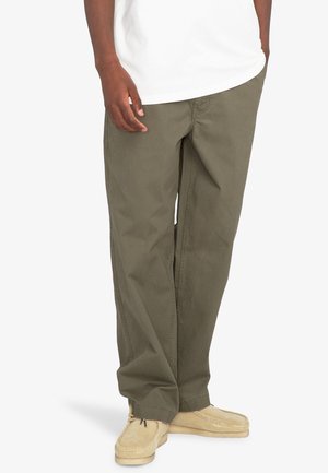 Olive green cotton pants with a relaxed fit, featuring straight legs and side pockets. Worn with beige suede shoes.
