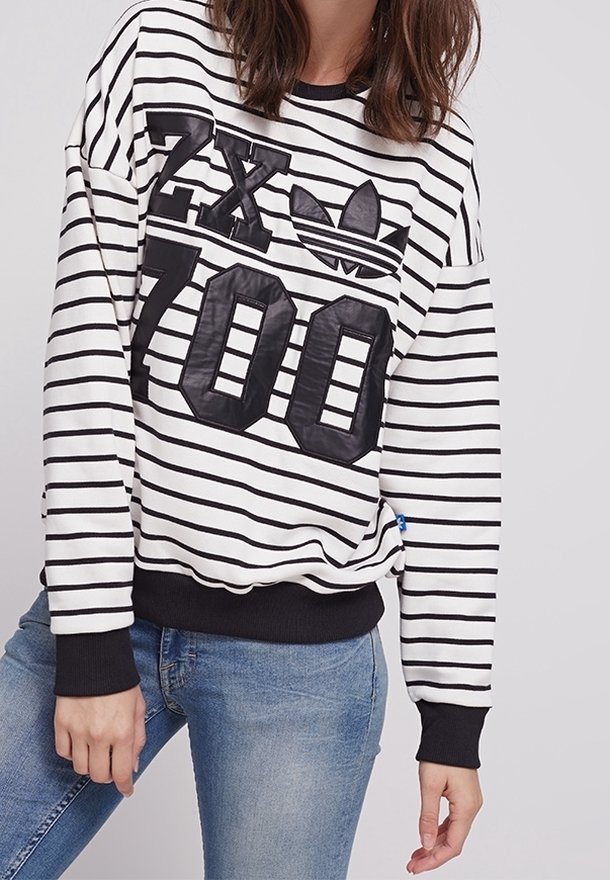 Bílá a černě pruhovaná mikina s velkým černým grafikem "ZX 700" a logem Adidas na přední straně, s žebrovanými manžetami a lemem.