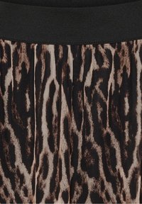 Nærbillede af plisseret stof med sort elastisk linning og et abstrakt mønster af mørkebrun og beige dyretryk.