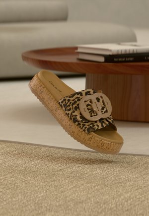 Slipper met luipaardprint en een dik kurken plateau, voorzien van een grote beige gesp op het bandje en een glad, gevormd voetbed.