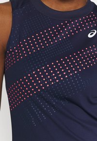 Débardeur de sport bleu marine avec un tissu texturé présentant des motifs de points rouges et bleus sur la poitrine, un col rond et une coupe sans manches.