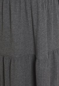 Grå ribbade klänning med skräddad tygdetaljer vid midjan, med en flödande kjol och mjukt, texturerat tyg.