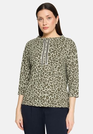 Olijfgroene top met een luipaardprint, driekwart mouwen en een centrale sluiting met twee contrasterende strepen.