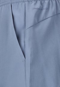 Lichtblauwe sportshorts hebben een elastische tailleband, een zijzak en een soepele, lichtgewicht stof met subtiele stiksels.