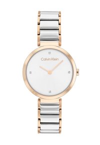 Montre Calvin Klein avec un boîtier rond en argent et or rose, cadran blanc avec quatre accents et un bracelet en maillons métalliques.