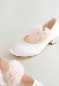 Pantofi cu toc joasă din satin alb, cu vârfuri rotunde, decorați cu flori din material roz deschis pe baretele de deasupra.
