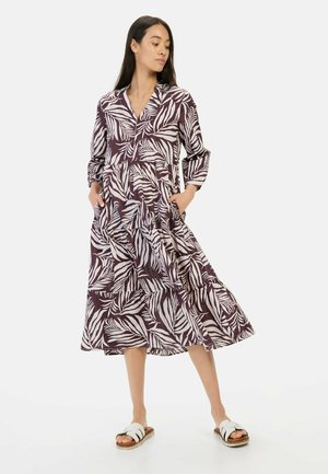 Langes, gestuften Kleid mit tiefem V-Ausschnitt in Dunkellila mit weißen Blattmustern. Es hat lange Ärmel, Seitentaschen und eine lockere Passform.