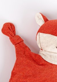 Soft plush toy in orange and cream fabric, featuring a fox design with pointed ears, a knotted tail, and stitched facial details.