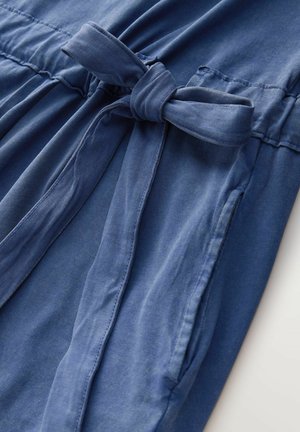 Rochie din țesătură albastr ă, cu talie legată, strângere elastică și buzunare laterale. Textura este netedă, cu un luciu subtil.