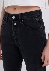 Svarta högmidjade jeans i denim med en klassisk femfickdesign, silverdetaljer och en liten broderad logotyp på midjebandet.