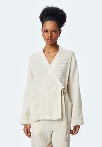 Beige wikkeljack met verticale strepen, lange mouwen en een strik taille. Zachte textuur en relaxte fit, gecombineerd met bijpassende broek.