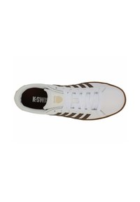 Scarpa atletica bianca con strisce marroni, design con lacci e suola in gomma. Presenta un logo sulla linguetta e una tomaia in tessuto liscio.
