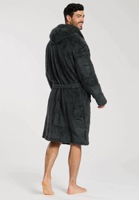 Peignoir à capuche gris foncé en matériau duveteux, doté d'une ceinture à nouer à l'avant, de poches latérales et d'une coupe mi-longue.