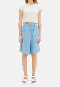 Lichtblauwe denim culottes met een elastische tailleband, twee zijzakken en een losse pasvorm. Gecombineerd met een witte cropped ribgewoven t-shirt.