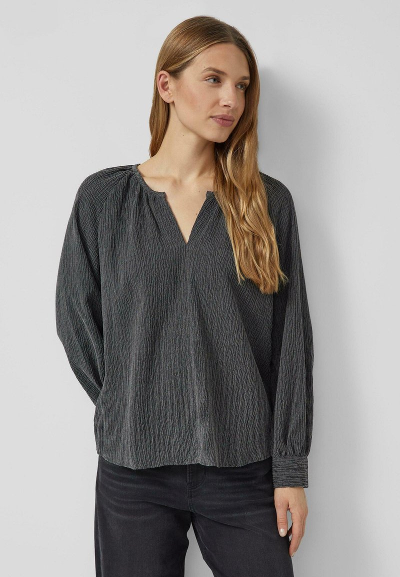 Long-sleeve, v-neck blouse in dark gray fabric with vertical stripes. Features gathered detailing along the neckline and cuffs.