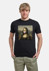 Camiseta de algodón negra que presenta una imagen impresa de la Mona Lisa con una burbuja de chicle rosa en la cara del sujeto. Mangas cortas y cuello redondo.