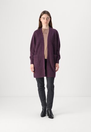 Purple, textured knit cardigan with open front, two front pockets, and long sleeves. Worn over a light beige top and paired with black jeans.