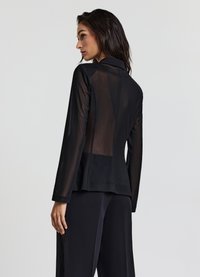 Blusa nera con schiena trasparente e maniche lunghe. Presenta un colletto strutturato e una vestibilità sartoriale. Tessuto liscio con dettagli di cucitura sottile.