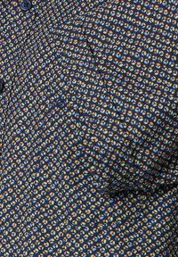 Navy blue shirt featuring a small, multicolored leaf pattern. Made of smooth fabric with a button closure and a stitched logo detail on the pocket.