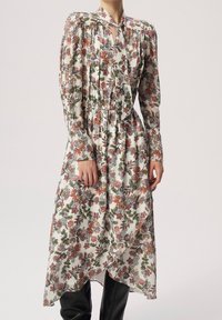 Blommönstrad lång klänning med nyckelhålsringning, puffärmar och asymmetrisk fåll. Lätt tyg med nyanser av vitt, rött, grönt och blått.