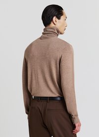 Brauner Rollkragenpullover aus weichem Strickmaterial, mit hohem Kragen und langen Ärmeln, kombiniert mit braunen Hosen und einem schwarzen Gürtel.