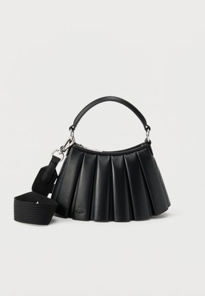 Zwarte leren handtas met plooien, voorzien van een korte handgreep en een afneembare brede stoffen schouderriem, tegen een witte achtergrond.