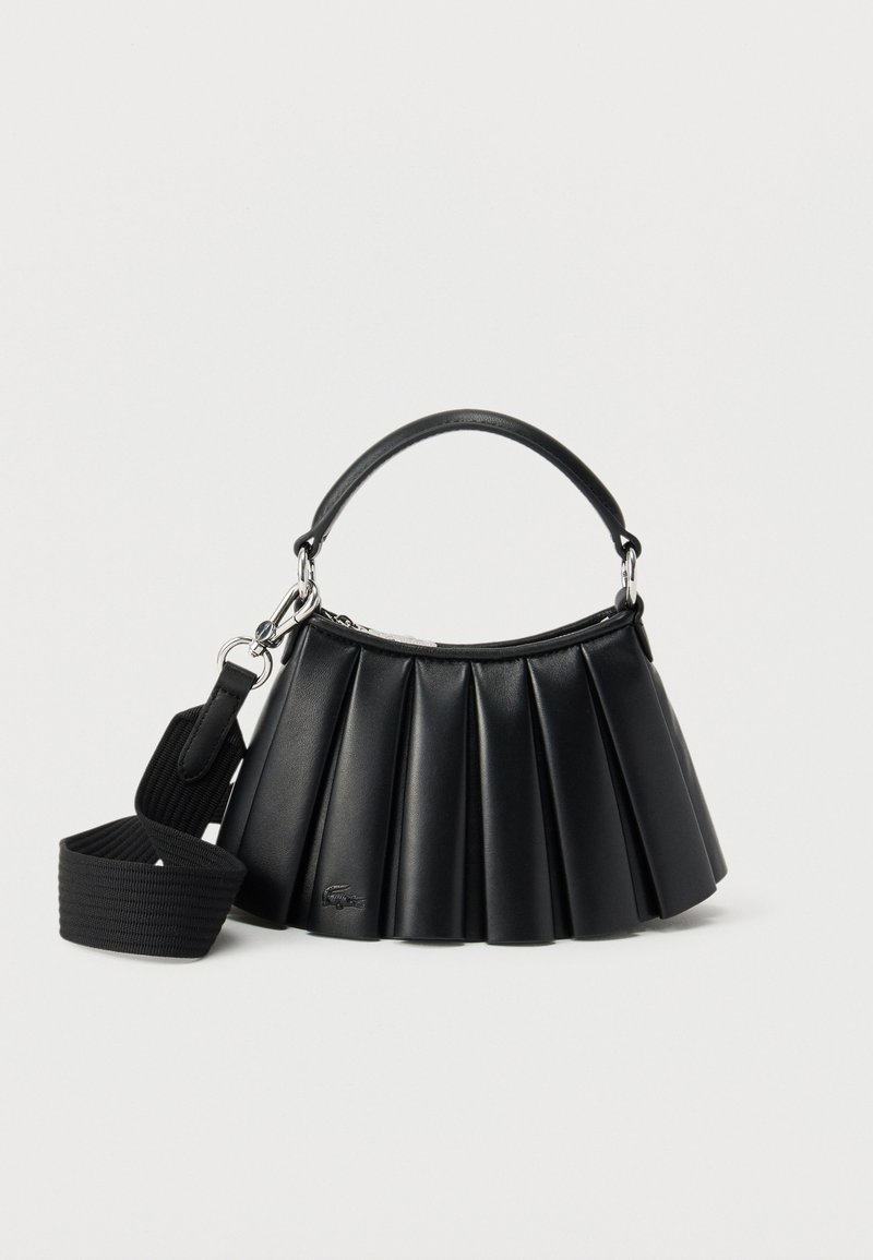 Μαύρη δερμάτινη τσάντα με πιέτες, με κοντό χερούλι και αποσπώμενο φαρδύ υφασμάτινο ιμάντα ώμου, σε λευκό φόντο.