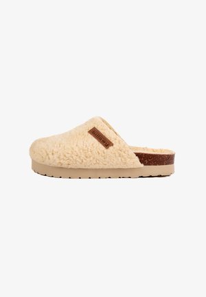 Chausson en fourrure de couleur crème, avec un dessus texturé, design à enfiler, et accent marron à l'arrière. Semelle douce avec un motif en zigzag.