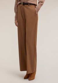 Ruskeat leveälahkeiset housut, valmistettu sileästä kankaasta, joissa sivutaskut, korkea vyötärö ja vastaava vyö. Koristeltu yksinkertaisella soljella.