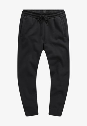 Pantalons de survêtement noirs en tissu texturé, dotés d'une taille élastique avec cordon de serrage, de poches latérales et d'un design fuselé ajusté.