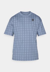 Lysblå kortærmet t-shirt med et gittermønster i mørkeblåt, med et lille sort logomerke øverst til venstre. Blødt bomuldsstof.