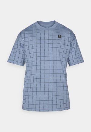 Lysblå kortærmet t-shirt med et gittermønster i mørkeblåt, med et lille sort logomerke øverst til venstre. Blødt bomuldsstof.