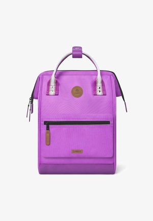 Sac à dos violet avec poignées argentées, poche zippée à l'avant, texture hexagonale et badge logo rond. Compartiment principal avec fermeture éclair.