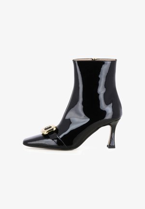 Bottine en cuir verni noir avec un bout pointu et une boucle dorée. Dotée d'un talon effilé et d'une surface lisse et brillante. Fermeture à glissière sur le côté.