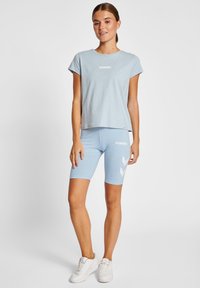 Lichtblauwe cropped t-shirt en bijpassende fietsho shorts met wit logo en chevronontwerp. Gladde katoenen stof, minimalistisch ontwerp.