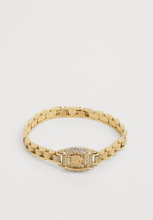 Zlatý kovový náramkový hodiniek s textúrovanými článkami, s obdĺžnikovým ciferníkom zdobeným detailným vzorom a akcentmi pripomínajúcimi diamanty.