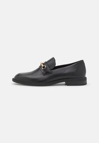 Mustad nahast loafers kuldse ratsapüksivöödetailiga, madalal kergel kontsal ja ümarate varvastega, shown külgprofiliga valgel taustal.