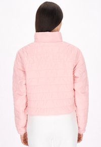 Puffy pink jakke med høj krave, med vandrette quiltede linjer, kort længde og lange ærmer. Glat, skinnende stoftekstur.