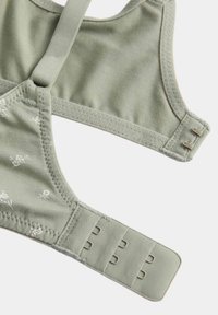 Soft green bra with floral pattern, adjustable straps, and triple hook-and-eye closures on a white background.