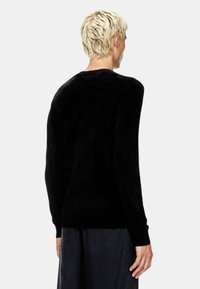Maglione nero in cashmere con una texture morbida, maniche lunghe, collo rotondo e vestibilità rilassata, visto da dietro senza loghi visibili.