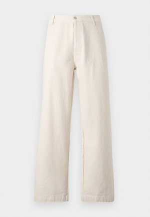 Pantalons large beige en coton. Présente une fermeture à bouton à l'avant, des passants de ceinture et un design épuré sans ornement, avec une finition texturée.