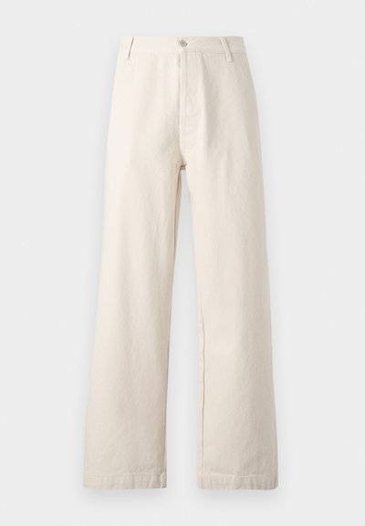 Bež hlače širokega kroja iz bombaža. Imajo zapiranje na gumb spredaj, zanke za pas in čist, neokrasen dizajn s teksturirano površino.