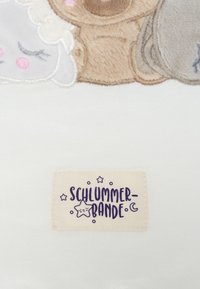 Bestickte Plüschfiguren in sanften Pastellfarben, die ein lächelndes Schaf und einen Bären zeigen, mit einem Stoffanhänger, der "SCHLUMMERBANDE" liest.