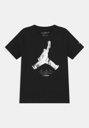 Černé tričko s krátkým rukávem s velkým stříbrným logem Jumpman a nápisem „I SUCCEED“ uprostřed přední strany.
