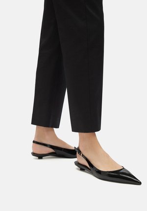 Černé lakované slingback baleríny s špičatou špičkou a nízkým podpatkem, s mírným leskem a popruhem s nastavovací sponou.