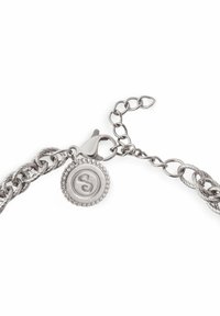 Bracelet en métal argenté avec un design de chaîne torsadée, comportant un pendentif circulaire gravé d'un "S" et une fermeture mousqueton.