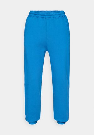 Niebieskie dresowe spodnie z elastycznym paskiem w talii, ściągaczami na kostkach i gładką fakturą. Bez kieszeni, z małym logo na lewej nogawce.