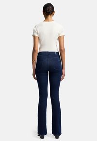 Jeans svasati blu scuro con vita alta, realizzati in denim. Presentano tasche posteriori cucite e una texture liscia e leggermente elasticizzata.