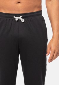 Zwarte katoenen sweats met een elastische tailleband, een trekkoordsluiting en zijzakken. Vlotte textuur en lichtgewicht ontwerp.