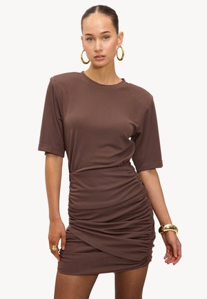 Vestido de punto marrón con mangas cortas, detalles fruncidos en los costados y una silueta ajustada. Presenta un escote redondo y una textura suave.